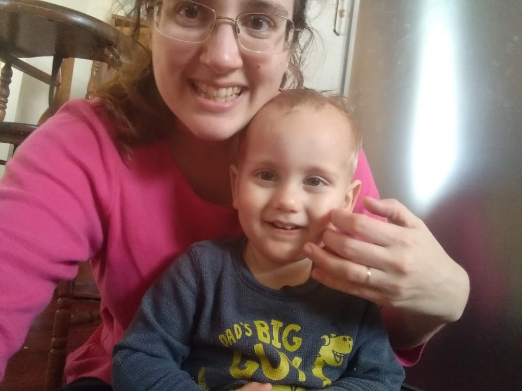 One-year-old Daniel is sitting on my lap while I tickle his cheek. We're both looking at the camera because a selfie was the only way I could get a good picture.